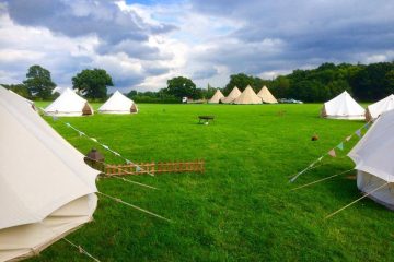 Bright green grass with bell tents in an open field